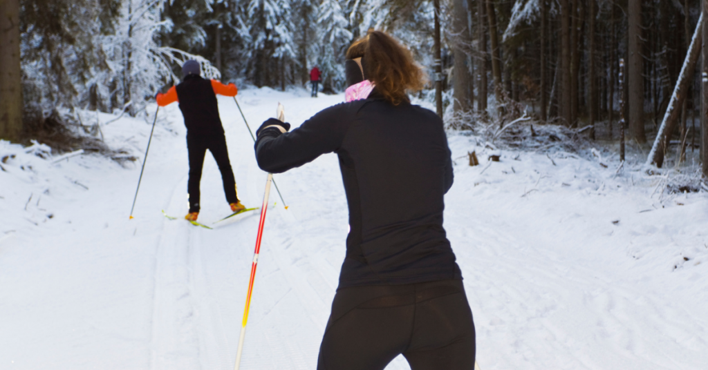 A woman cross country skiing in a snowy forest. 